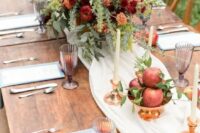 05 a beautiful apple orchard wedding with a neutral runner, a bold centerpiece of orange, burgundy and yellow blooms, greenery and thistles, apples and tall and thin candles