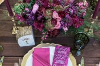 06 a beautiful berry-tone wedding centerpiece with deep purple, pink, purple blooms, greenery and matching purple candles