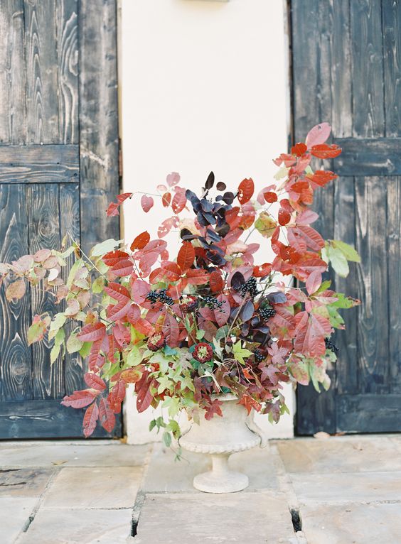 a bold fall wedding centerpiece of berries, dark and green leaves is a catchy idea for those who want a non-floral arrangement