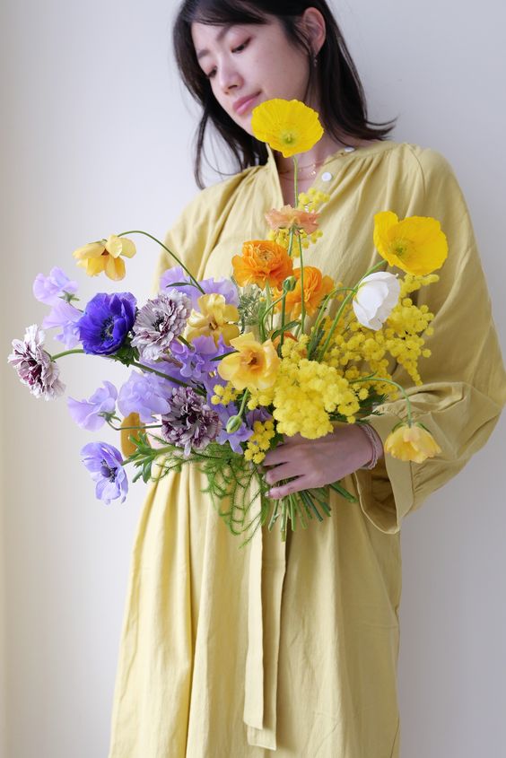 a colorful wedding bouquet of mimosa, poppies and other blooms done in purple and yellow is all about color blocking