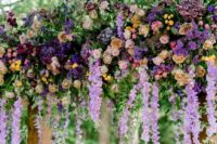 10 a colorful wedding arch with wsiteria, pink and yellow gardne roses, burgundy and violet blooms and greenery for a bright wedding
