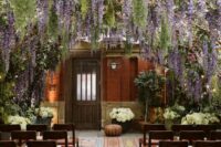 11 a dreamy wedding ceremony space with rows of matching chairs and wisteria naturally hanging over the space