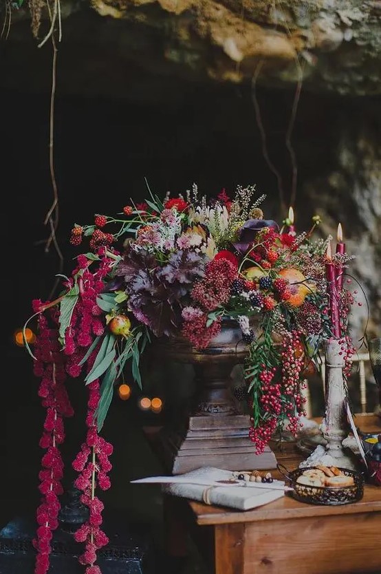 a luxurious wedding centerpiece with cascading blooms and foliage, colored fall leaves and berries