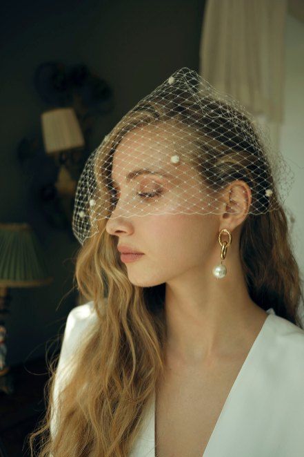a modern take on a birdcage veil with baroque pearls and a matching pearl earring create a fantastic and fashionable look