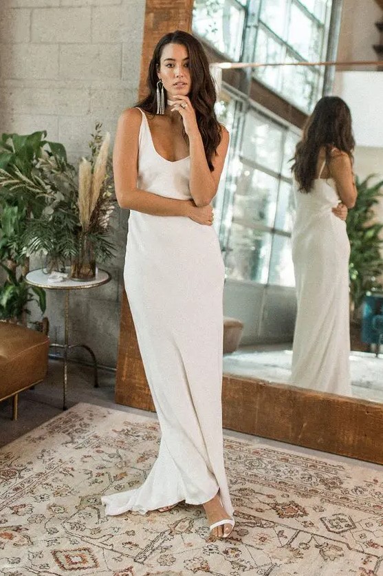 a modern relaxed plain slip wedding dress with a deep V-neckline plus statement earrings for an edgy look