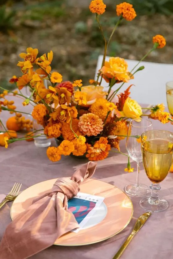 a bold wedding centerpiece of marigolds, mums, orchids and roses is a very beautiful and exquisite idea for a summer or fall wedding