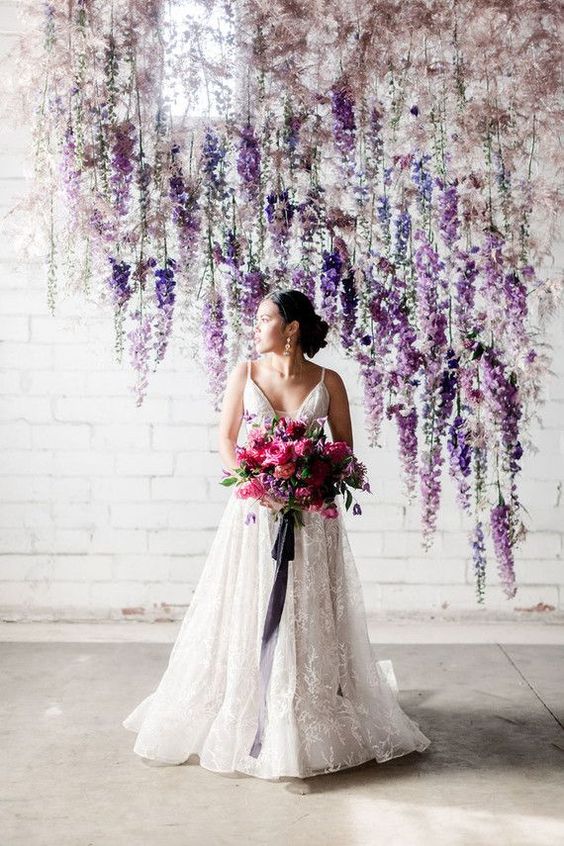 a gorgeous indoor wedding backdrop composed of hanging blooms and colorful dried leaves including wisteria is an amazing idea