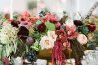 15 a lush and colorful fall wedding centerpiece of pink, mauve, burgundy, blush blooms, greenery and grapes plus a feather