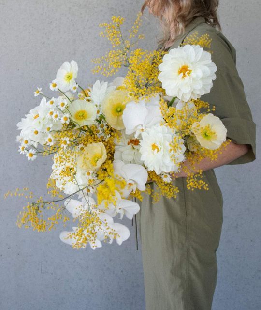 a lush wedding bouquet of white and yellow blooms including mimosa and orchids is a lovely and bright idea