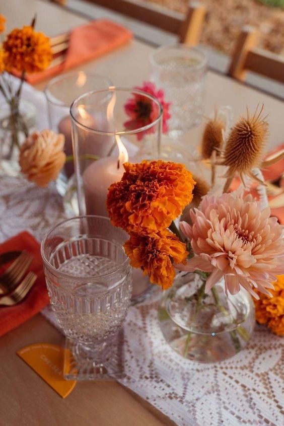 a cluster wedding centerpiece of marigolds, blush dahlias, grasses and blush candles is a cool idea for the wedding
