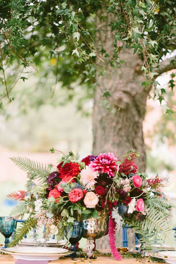 a colroful wedding centerpiece of blush dahlias and peonies, pink peonies and ranunculus, red and coral dahlias, ferns and amaranthus