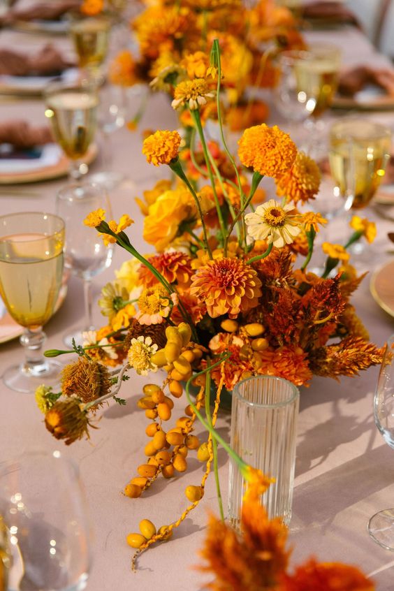 a dahlias, marigolds, carnations and some matching berries can create a bold centerpiece for a fall wedding