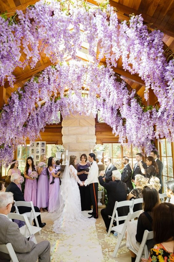a romantic indoor wedding ceremony space with wisteria hanging down from the ceiling to make it feel more outdoorsy