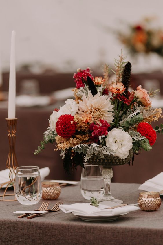 a chic and bold wedding centerpiece of white lisianthus, burgundy mums, hydrangeas, some dried blooms and pale miller