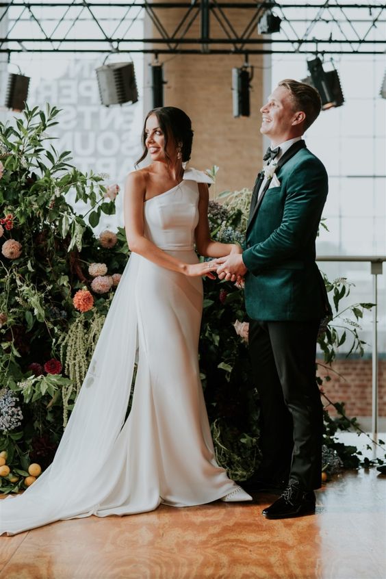 a modern off the shoulder mermaid wedding dress with a bow on the shoulder and a train is a chic idea for a modern glam wedding