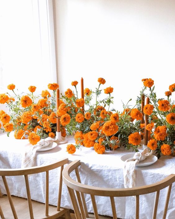 a fantastic wedding tablescape all done with marigolds, with orange candles and white linens is a stylish and bold idea