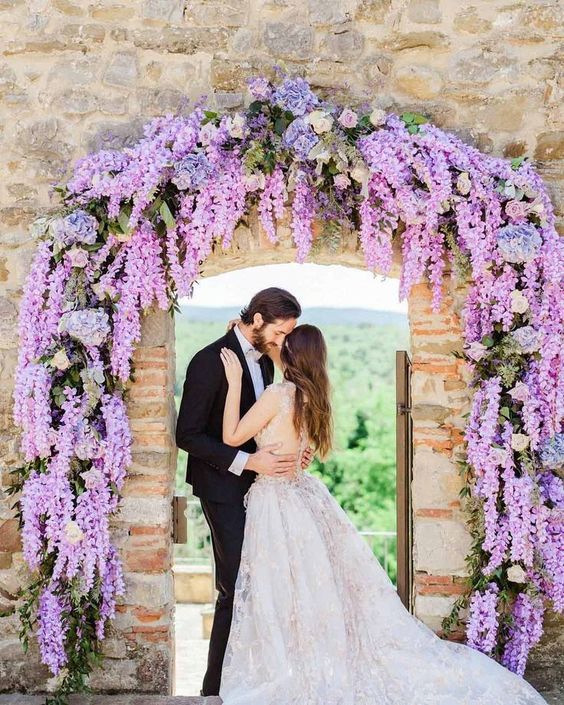 a wisteria wedding arch with roses and hydrangeas is a lovely idea for a spring or summer wedding