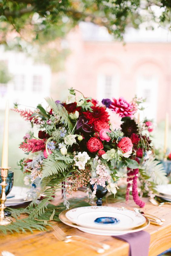 a jewel-tone wedding centerpiece of dark callas, pink and white dahlias, pink peony roses, greenery and amaranthus is perfect for the fall