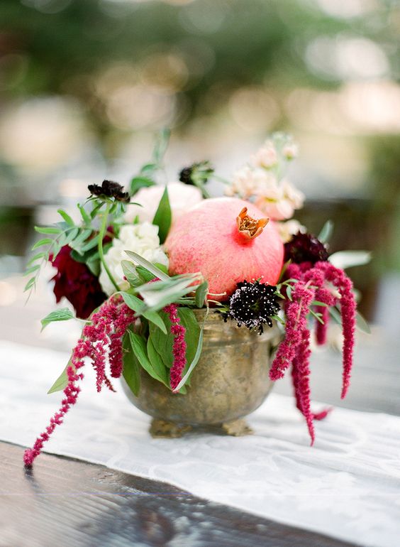 a chic fall wedding centerpiece of white and burgundy peonies, deep purple blooms, a pomegranate, amaranthus is a cool idea