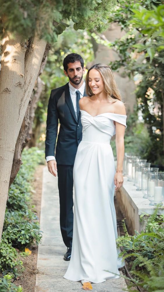 a modern off the shoulder wedding dress with a draped bodice and a pleated skirt with a train is a lovely idea for a modern wedding