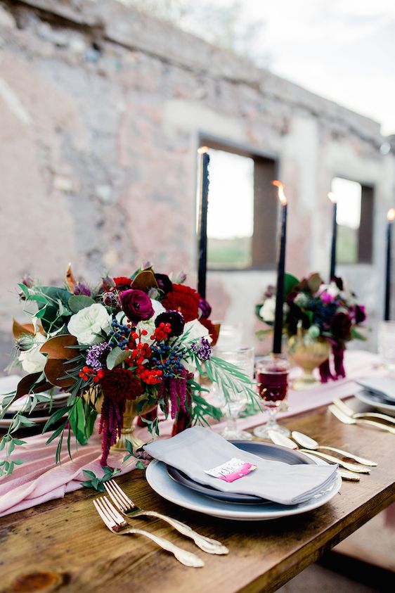 a chic fall wedding centerpiece of red and white roses, deep purple and fuchsia blooms, berries, greenery and amaranthus