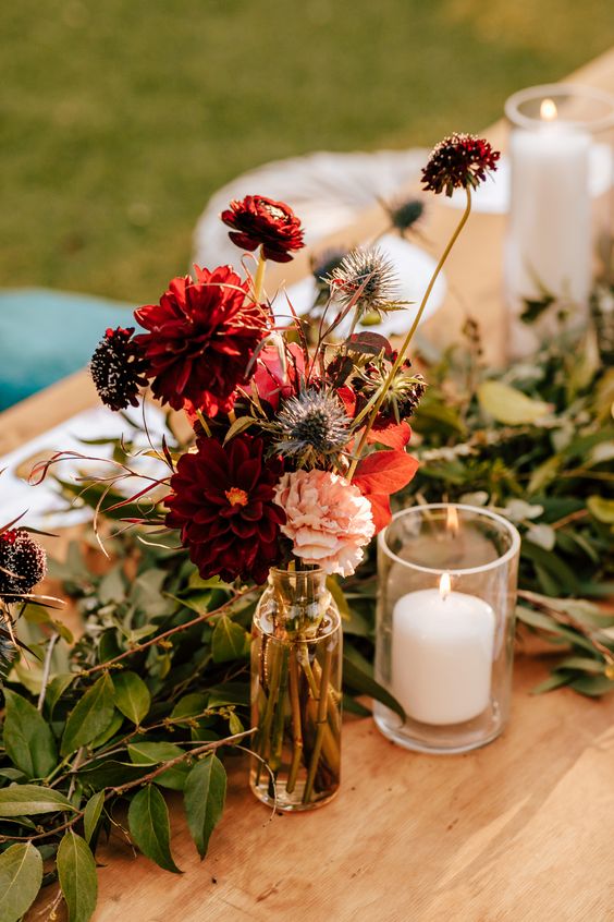 a fall wedding centerpiece of burgundy mums, blush ones, deep purple blooms, thistles and bold fall foliage is easy to repeat
