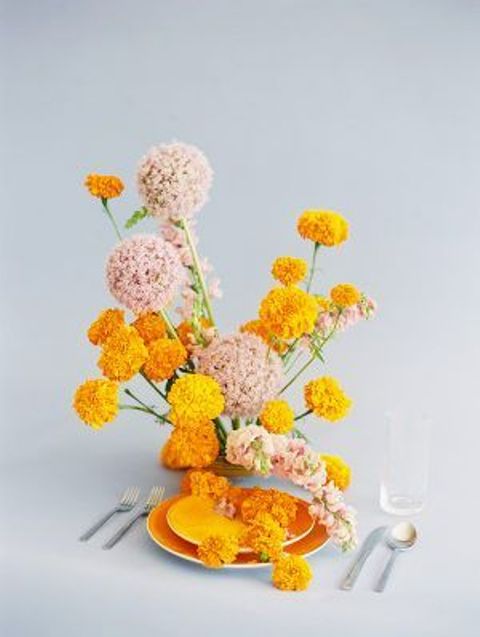 a pretty wedding place setting with orange porcelain, marigolds and blush blooms, cutlery is a very bold and cool idea