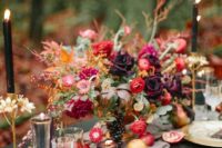 27 a jewel tone wedding centerpiece with lots of greenery, red, pink and purple blooms and grapes, candles and apples on the table