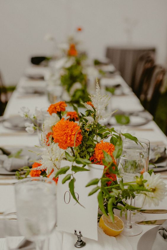 a simple and bold wedding centerpiece of greenery, fillers and white dahlias plus marigolds can be DIYed easily