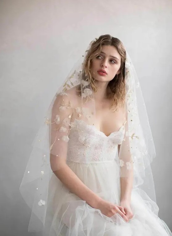 a subtle and beautiful wedding veil with white fabric blooms, gold embroidery and pearls and rhinestones is a lovely solution