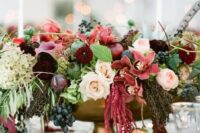 28 a lush and colorful fall wedding centerpiece of pink, mauve, burgundy, blush blooms, greenery and grapes plus a feather