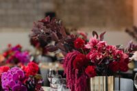29 a bold wedding centerpiece of amaranthus, dark foliage, red mumes, pink lilies and a shiny gold vase