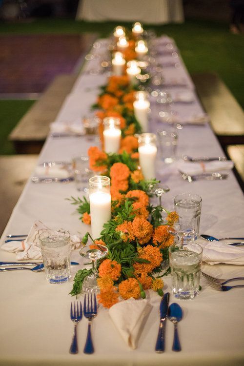 a stylish and easy wedding tablescape with marigolds and greenery, pillar candles, elegant cutlery and glasses is a cool and budget-friendly idea
