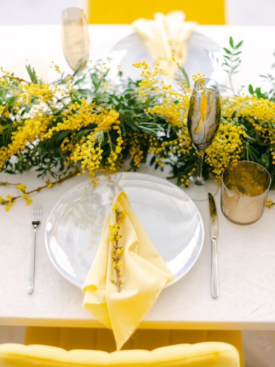 a bright and lively wedding tablescape with a mimosa runner, white porcelain and yellow napkins plus grey glasses