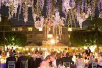 30 a cozy outdoor wedding ceremony space with wisteria hanging down, some candle lanterns and lights all over the space