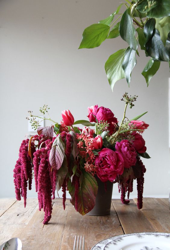 a vibrant wedding centerpiece of pink peonies, amaranthus, greenery and dark foliage is a chic and cool idea for summer or fall