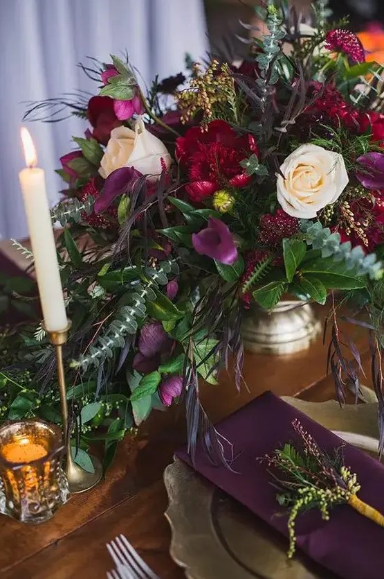 a purple, hot red floral wedding centerpiece with textural greenery and dark foliage is gorgeous for a moody fall wedding