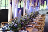 34 a gorgeous bold wedding reception space with wisteria hanging down, with greenery and bold purple blooms on the table, violet porcelain and lilac candles