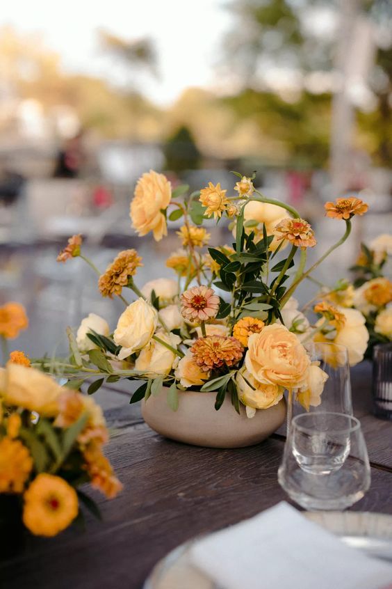 a yellow wedding centerpiece of ranunculus and marigolds is a cool idea for many weddings throughout the year