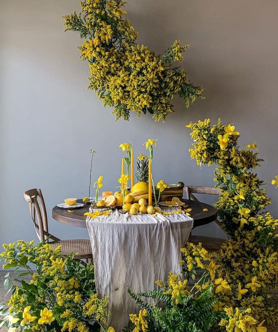 a jaw-dropping wedding sweetheart table surrounded with mimosa, with daffodils and yellow candles on the table