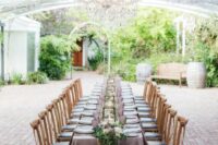 37 a lovely wedding reception space with wisteria naturally growing over it, with a table and a lilac tablecloth, purple glasses and greenery