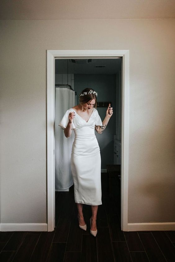 a modern plain midi wedding dress with a deep V-neckline and short sleeves is a timeless idea that will work for most modern weddings