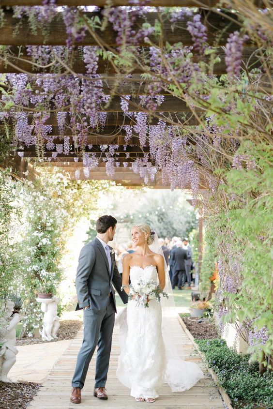 a lovely wedding walkway covered with wisteria, with greenery and blooms all over, is a chic and Instagrammable location