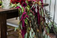 38 a lush wedding table runner of greenery, red roses and dahlias, berries and amaranthus for a bold fall wedding