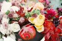 38 an adorable fall wedding centerpiece of a grey vase, yellow, pink and deep red blooms, fall leaves and pomegranates that help to embrace the fall