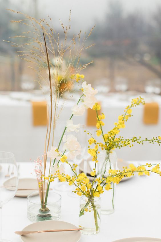 a modern cluster wedding centerpiece of mimosa, some dried herbs and neutral blooms is a catchy and cool idea