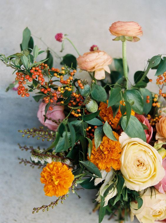 a bold wedding bouquet of blush and neutral ranunculus, berries, greenery and marigolds is a lovely idea for a garden wedding