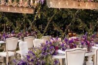 40 a luxurious and sophisticated wedding reception space with chandeliers with wisteria, a lush wedding table runner with purple blooms and greenery