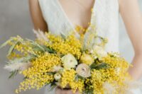 40 a pretty wedding centerpiece with ranunculus, mimosa and pampas grass is a lovely idea for a spring wedding