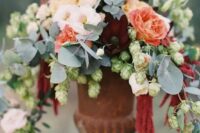 40 a soft wedding centerpiece of blush and red orange blooms plus pale greenery in a vintage urn